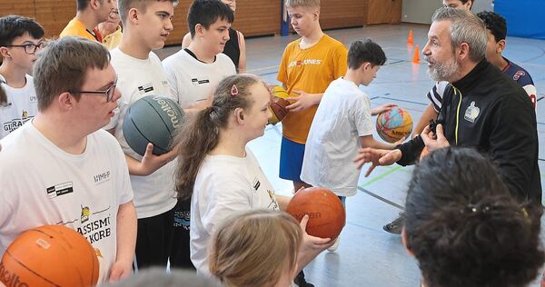 Marc Salzer, der Vereinskoordinator der MHP-Riesen, erklärt den Schülern das Dribbeln mit dem Basketball.
