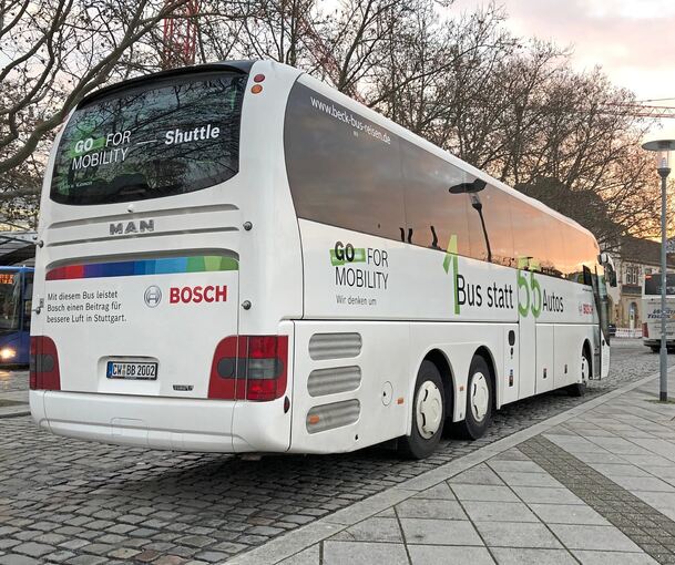 „1 Bus statt 55 Autos“ ist auf der rechten Seite dieses am Feuerbacher Bahnhof stehenden Bosch-Werkbusses plakatiert. Der Satz drückt den Nachhaltigkeitsgedanken aus, der hinter dem Angebot der Werkbusse steht.