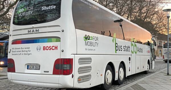 „1 Bus statt 55 Autos“ ist auf der rechten Seite dieses am Feuerbacher Bahnhof stehenden Bosch-Werkbusses plakatiert. Der Satz drückt den Nachhaltigkeitsgedanken aus, der hinter dem Angebot der Werkbusse steht.