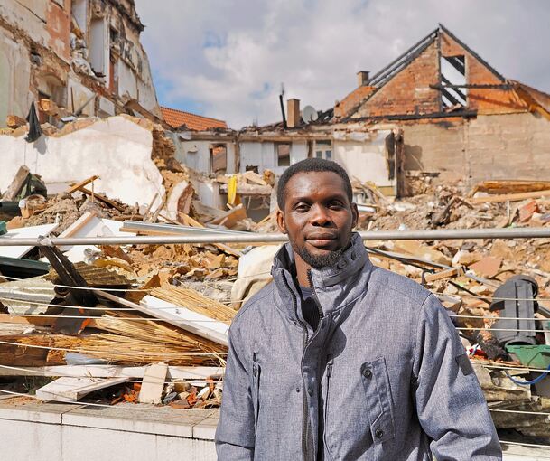 Modou Faal steht vor den Trümmern des Hauses, in dem er bis vor wenigen Wochen gewohnt hat. Sein Hab und Gut ist entweder verbrannt oder befindet sich in den Trümmern.
