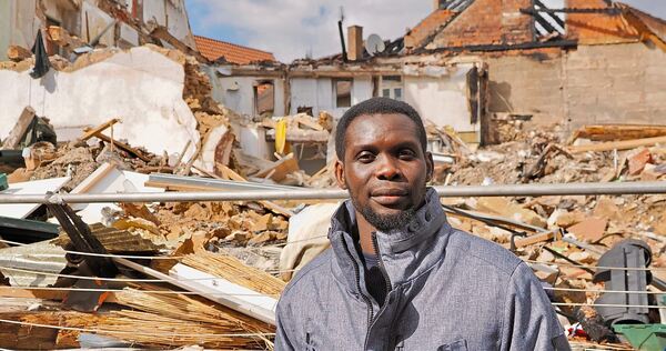 Modou Faal steht vor den Trümmern des Hauses, in dem er bis vor wenigen Wochen gewohnt hat. Sein Hab und Gut ist entweder verbrannt oder befindet sich in den Trümmern.