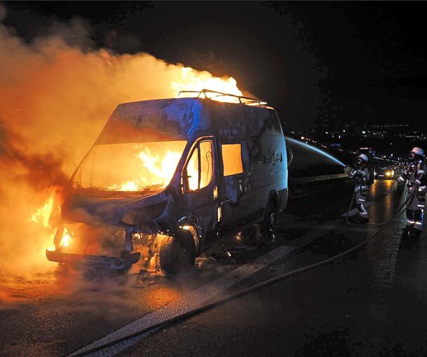 Der Transporter steht im Vollbrand, die Feuerwehr löscht.