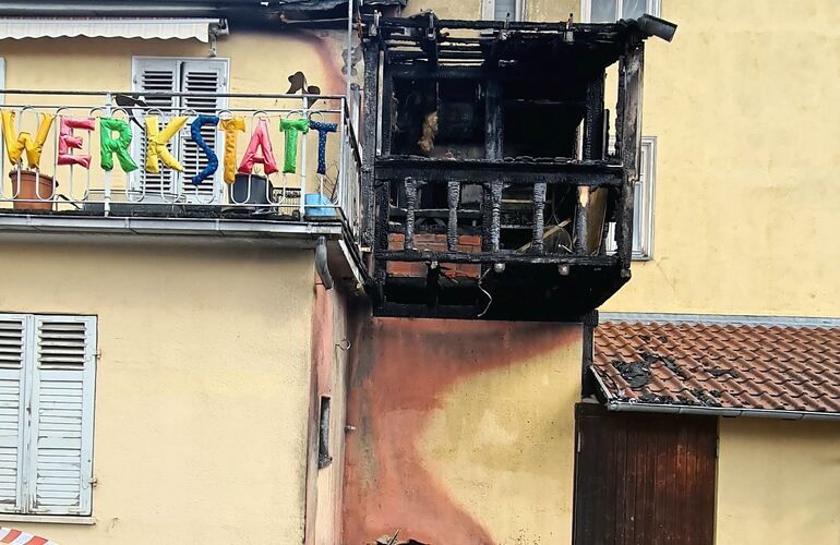 Unterhalb der hölzernen Balkons befand sich der Müllcontainer, der am Samstag gegen 2.20 Uhr in Brand gesetzt wird. Das Feuer zerstört den Balkon vollständig, ein Fenster zerspringt, Rauch dringt ins Gebäude.