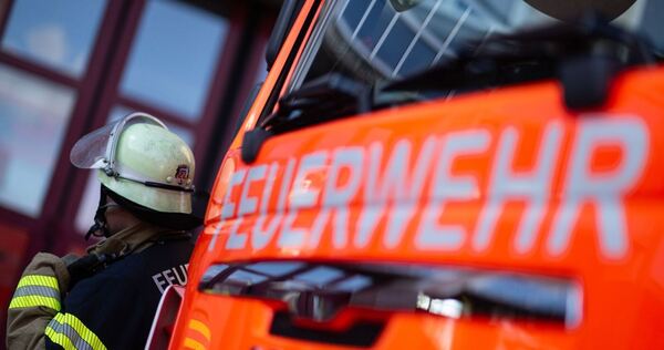 Feuerwehrmann steht neben einem Feuerwehrauto (Symbolbild)