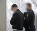 Der Hauptangeklagte wird von einem Justizbeamten im Landgericht zum Prozess gebracht.