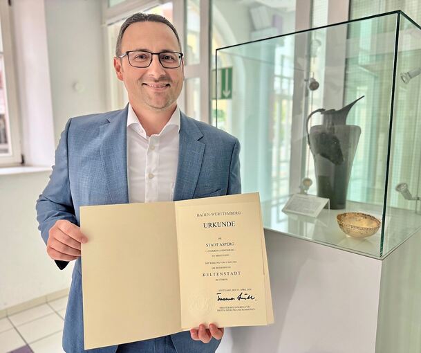 Der Asperger Bürgermeister Christian Eiberger mit der Urkunde des Landes.