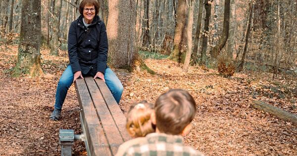 Auf einem Spielplatz im Wald haben Beate Volmari und ihre Enkel Spaß.
