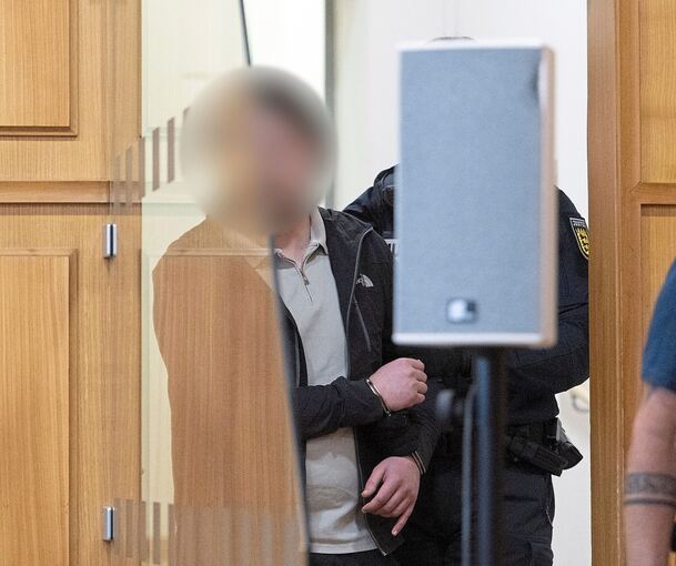 Einer der beiden Angeklagten – er soll geschossen haben – wird in den Verhandlungssaal geführt.