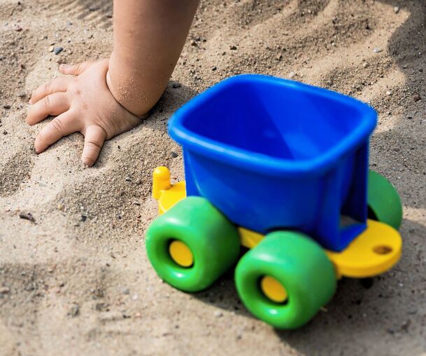 Ein Kind spielt im Sandkasten einer Kita.