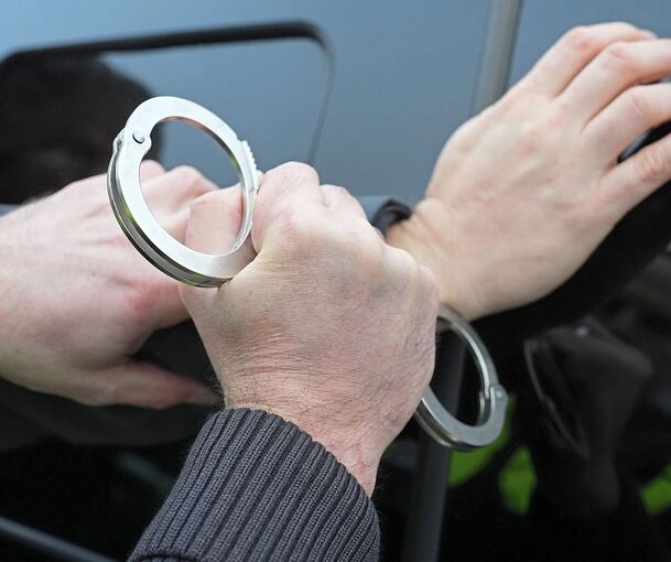Ein Polizist legt einem Mann Handschellen an.