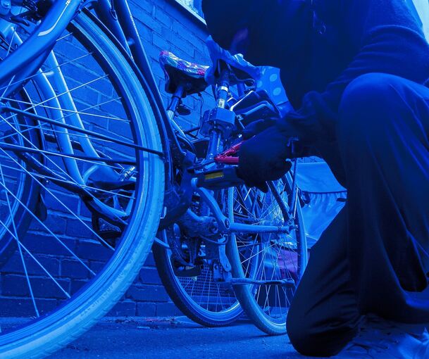 Ein Fahrraddieb macht sich an einem Fahrrad zu schaffen.