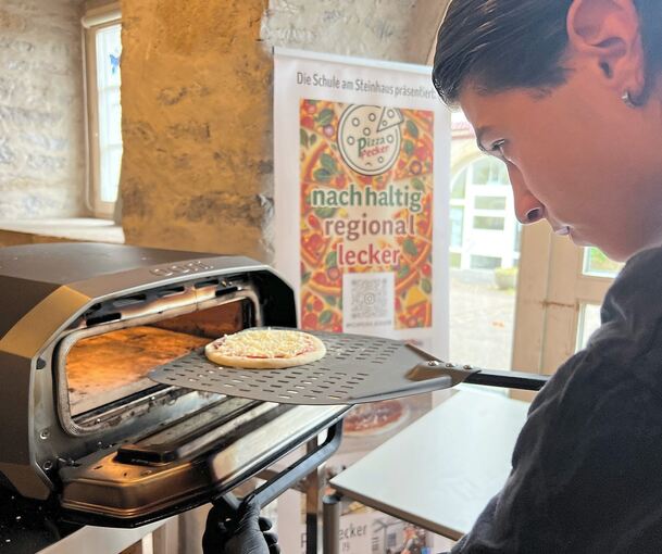 Eine Pizza wird in den Solarofen geschoben.