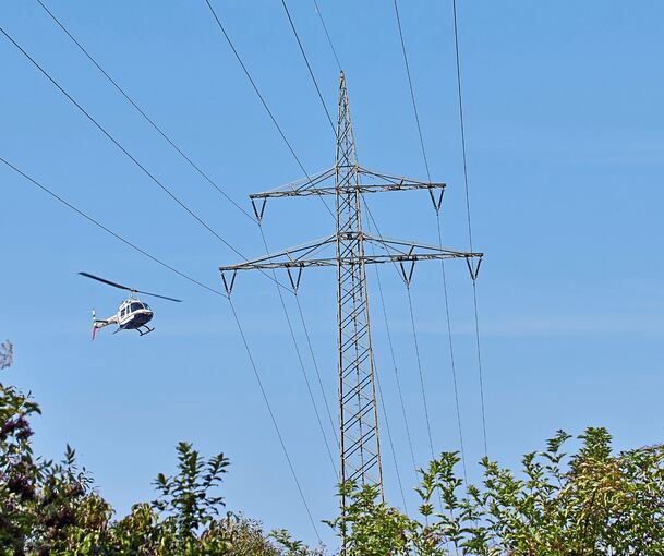 Mit nur wenigen Metern Abstand werden die Hochspannungsfreileitungen mit dem Helikopter abgeflogen und kontrolliert. Mit nur wenigen Metern Abstand werden die Hochspannungsfreileitungen mit dem Helikopter abgeflogen und kontrolliert.