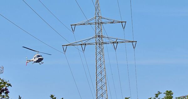 Mit nur wenigen Metern Abstand werden die Hochspannungsfreileitungen mit dem Helikopter abgeflogen und kontrolliert.