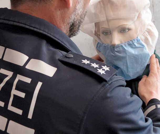 Ein Polizist demonstriert die Anwendung einer Spuckschutzhaube an einer Puppe. Ein Polizist demonstriert die Anwendung einer Spuckschutzhaube an einer Puppe.