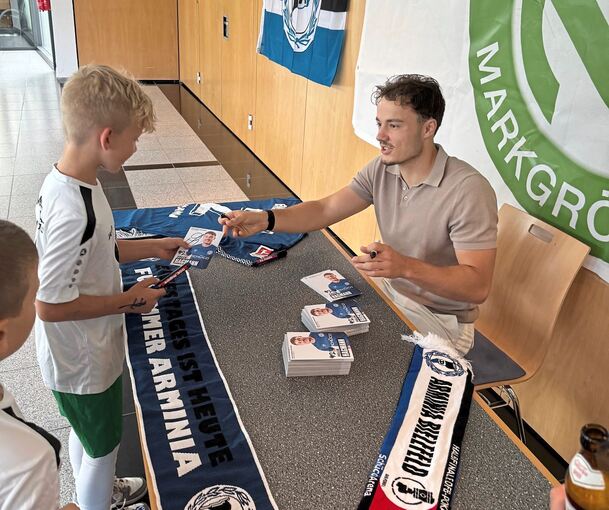 Fußballprofi Felix Hagmann (rechts) schreibt fleißig Autogramme für den Nachwuchs.