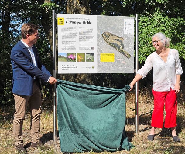 Ulrike Möck vom Regierungspräsidium Stuttgart und Gerlingens Bürgermeister Dirk Östringer enthüllen eine der neuen Infotafeln auf der Gerlinger Heide.