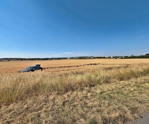 Nach einem Unfall landet ein PKW auf einem Feld.