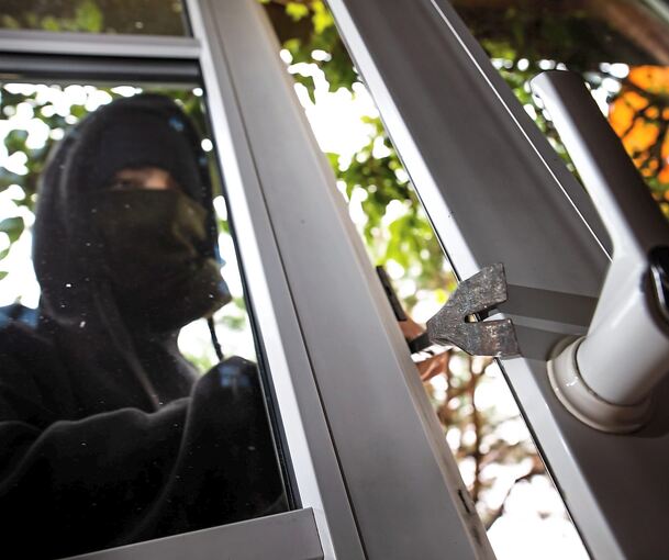 Ein Mann hebelt gewaltsam ein Fenster auf.
