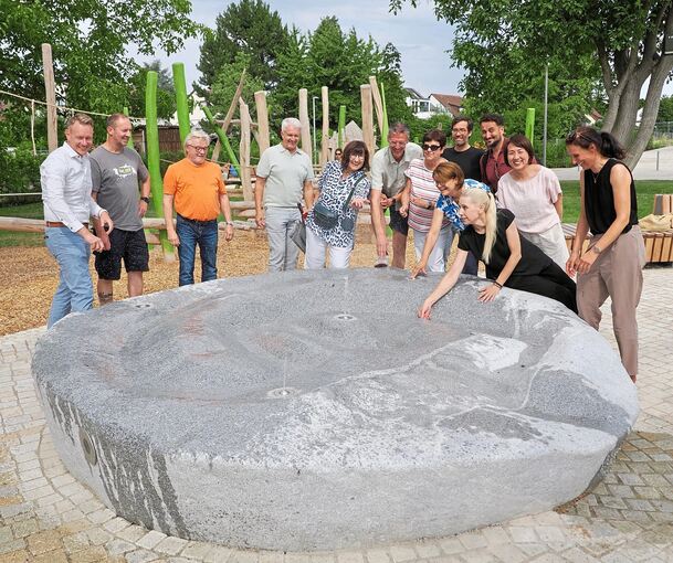 Das Herzstück des Quartiersplatzes ist ein tonnenschwerer Granit, der nach dem Druck auf den Sensor Wasserfontänen von sich gibt. Das begeisterte bei der Eröffnung auch Bürgermeister Sebastian Mannl (links) Stadträtinnen und Stadträte sowie Projektve