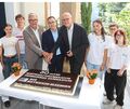 Umringt von Schülern schneiden (von links) Landrat Dietmar Allgaier, Staatssekretär Andreas Deuschle und Schulleiter Stefan Ranzinger die Jubiläumstorte an.