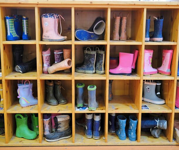 Kinderstiefel stehen in einem Kindergarten in einem Regal. Die Stadt Freiberg möchte die Kita-Gebühren erhöhen.