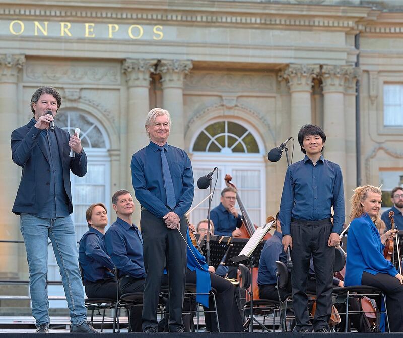Dirigent Jan Caeyers (Mitte) und Pianist Kit Armstrong (rechts) werden von Intendant Lucas Reuter zum zweiten Mal am Monrepos begrüßt, nachdem sie schon am Vorabend auf der Bühne standen.