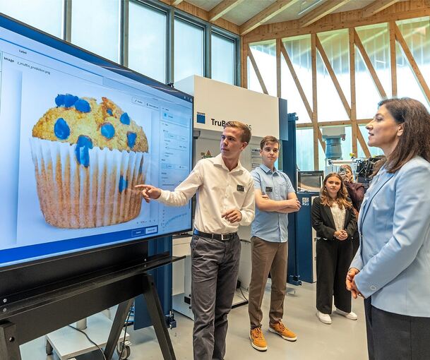 Bundeswirtschaftsministerin Katherina Reiche zu Besuch bei Trumpf: Anhand eines Muffins erklären die Auszubildenden, wie sie ihre KI trainieren.