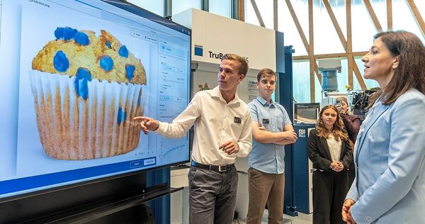 Bundeswirtschaftsministerin Katherina Reiche zu Besuch bei Trumpf: Anhand eines Muffins erklären die Auszubildenden, wie sie ihre KI trainieren.