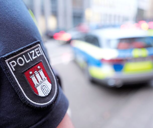 Ein Polizist steht vor einem Einsatzfahrzeug.