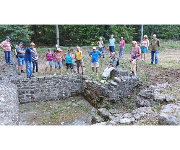 Besucher der Führung vor einem der Keller mit Mauern aus gewachsenem Fels und behauenen Steinen. Erläuterungen von Micha Bachtel Besucher der Führung vor einem der Keller mit Mauern aus gewachsenem Fels und behauenen Steinen. Erläuterungen von Micha Bachteler (mit Hut).