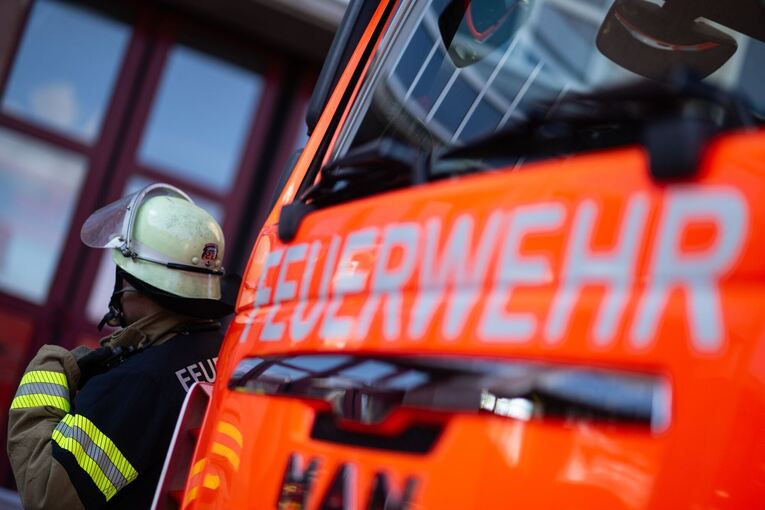 Feuerwehrmann steht neben einem Feuerwehrauto (Symbolbild) Feuerwehrmann steht neben einem Feuerwehrauto (Symbolbild)