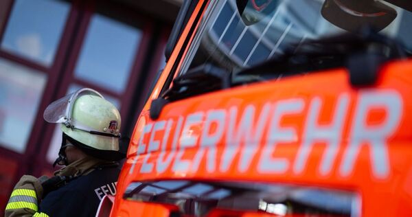 Feuerwehrmann steht neben einem Feuerwehrauto (Symbolbild) Feuerwehrmann steht neben einem Feuerwehrauto (Symbolbild)
