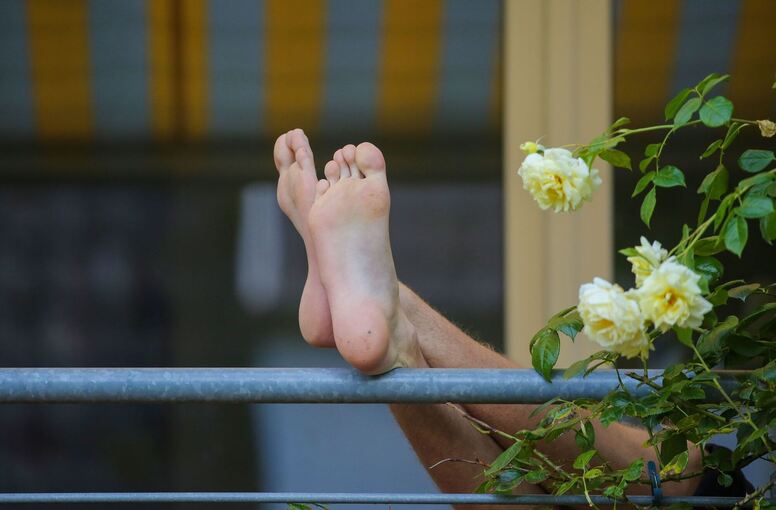 Die Füße eines Mannes sind auf einem Balkon zu sehen Die Füße eines Mannes sind auf einem Balkon zu sehen