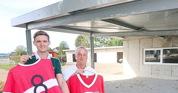 Uwe Düding (links) und Helmut Pistorius vom GSV-Förderverein hoffen auf einen hohen Erlös für die beiden Trikot-Raritäten. Im Hi Uwe Düding (links) und Helmut Pistorius vom GSV-Förderverein hoffen auf einen hohen Erlös für die beiden Trikot-Raritäten. Im Hintergrund sind das neue Hüttle (rechts) und links dahinter das Materiallager zu sehen.