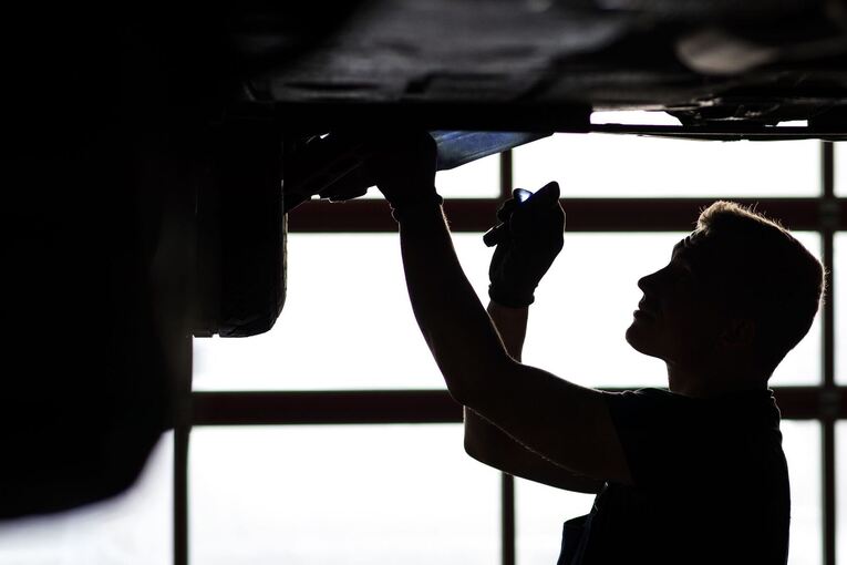 Ein Mechaniker begutachtet ein Auto in einer Werkstatt Ein Mechaniker begutachtet ein Auto in einer Werkstatt