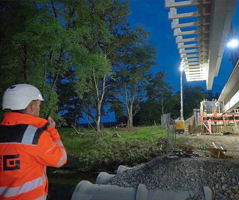 Per Funk dirigiert ein Arbeiter am Boden den Träger an seinen vorbestimmten Ort. Per Funk dirigiert ein Arbeiter am Boden den Träger an seinen vorbestimmten Ort.