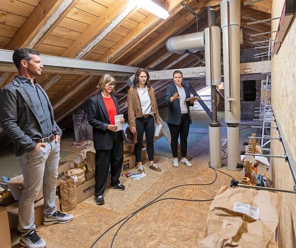 Unter dem Dach aus dem 18. Jahrhundert entsteht aktuell eine moderne Heizungszentrale. Bei einem Pressetermin informiert Bürgermeisterin Andrea Schwarz (zweite von rechts) mit ihrem Team über den Sanierungsfortschritt.