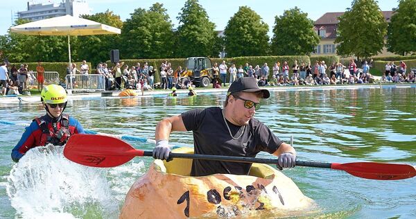 Viele Menschen haben zugeschaut, als Männer und Frauen in Riesenkürbissen über den See gepaddelt sind.