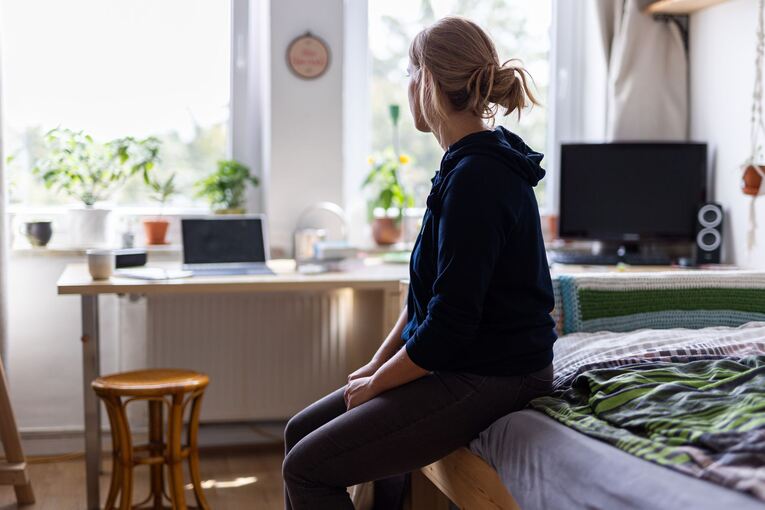 Eine Studentin sitzt auf dem Bett in ihrem WG-Zimmer Eine Studentin sitzt auf dem Bett in ihrem WG-Zimmer