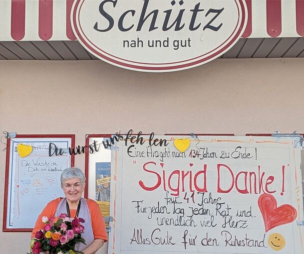 Mit einem großen Strauß Rosen in der Hand steht Sigrid Schütz vor ihrem Laden und wird von ihren Stammkunden verabschiedet.