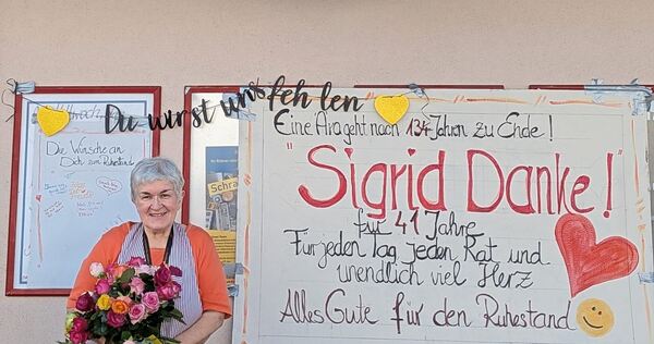 Mit einem großen Strauß Rosen in der Hand steht Sigrid Schütz vor ihrem Laden und wird von ihren Stammkunden verabschiedet.