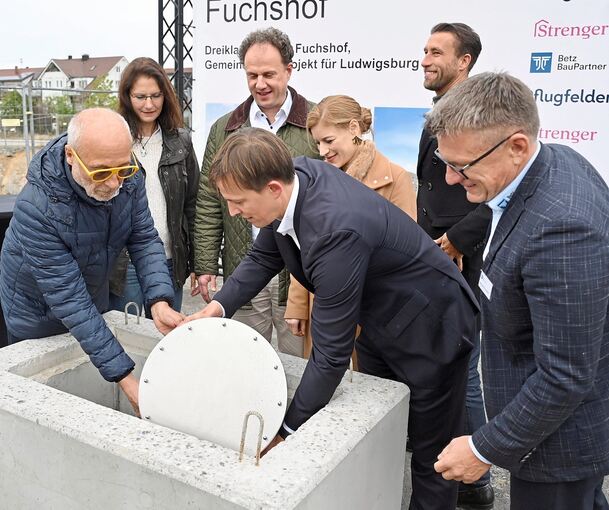 Die Zeitkapsel wird von Jürgen Pflugfelder (links) und Daniel Hannemann (Strenger, vor Lis Hannemann-Strenger) in dem Quader versenkt. Zuvor hatten OB Matthias Knecht mit Bürgermeisterin Andrea Schwarz (hinten links), Julian Pflugfelder (2.v.r.), Han