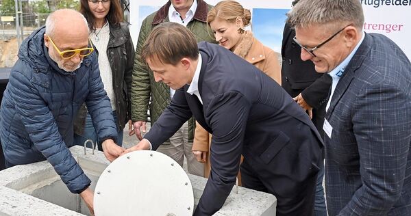 Die Zeitkapsel wird von Jürgen Pflugfelder (links) und Daniel Hannemann (Strenger, vor Lis Hannemann-Strenger) in dem Quader versenkt. Zuvor hatten OB Matthias Knecht mit Bürgermeisterin Andrea Schwarz (hinten links), Julian Pflugfelder (2.v.r.), Han